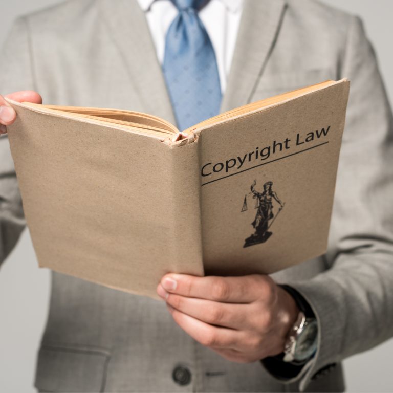 an frontal image of a person dressed in a beige suit with a blue tie reading up on fair use and coyright compliance for creatives