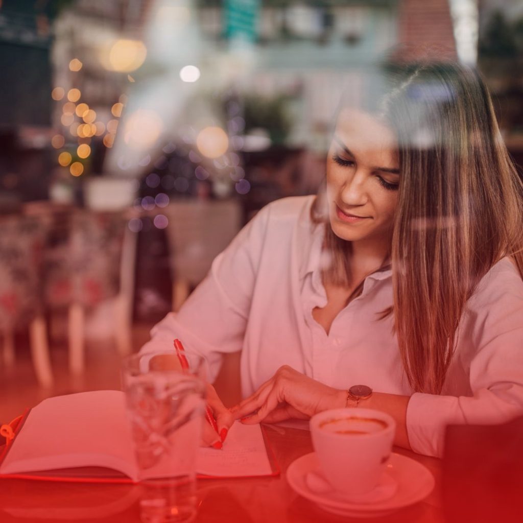 a female writer with blonde hair sitting in a coffee shop brainstorming the author authority that she would like to establish