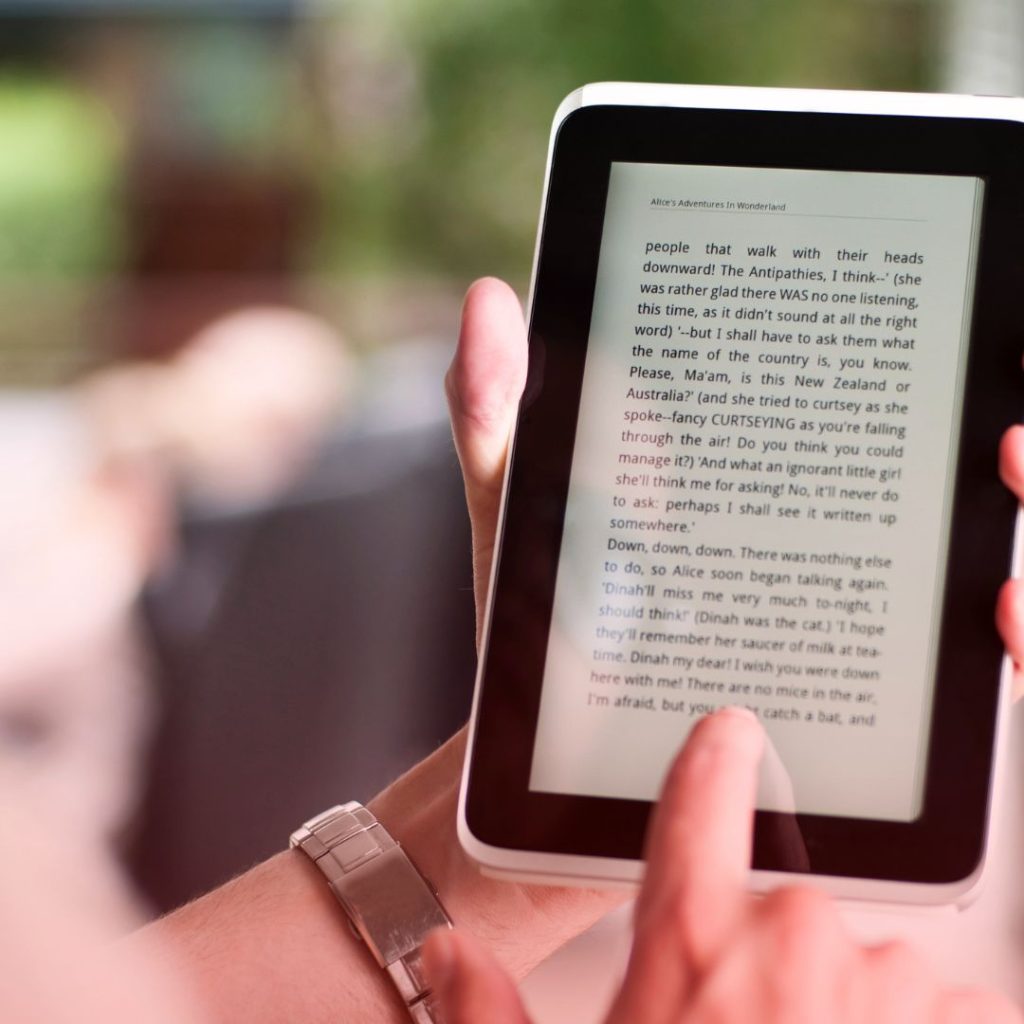 A person reading books on their Kindle in the public domain that is available to read for free