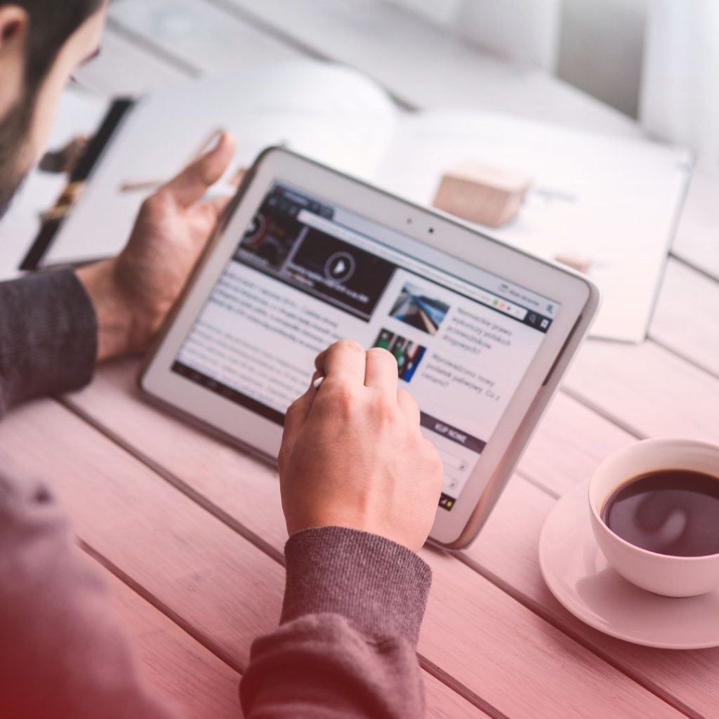 a man sitting at a table with a cup of coffee and a tablet exploring digital publishing tools