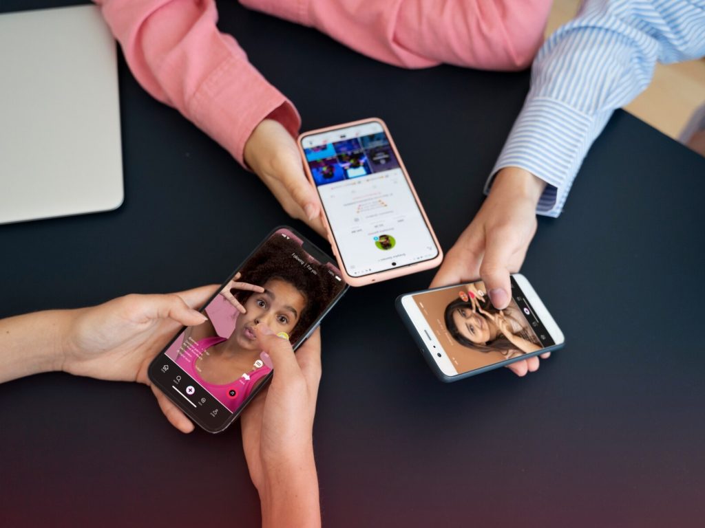 a group of people sitting around a table with their smartphones exploring the influencer marketing society