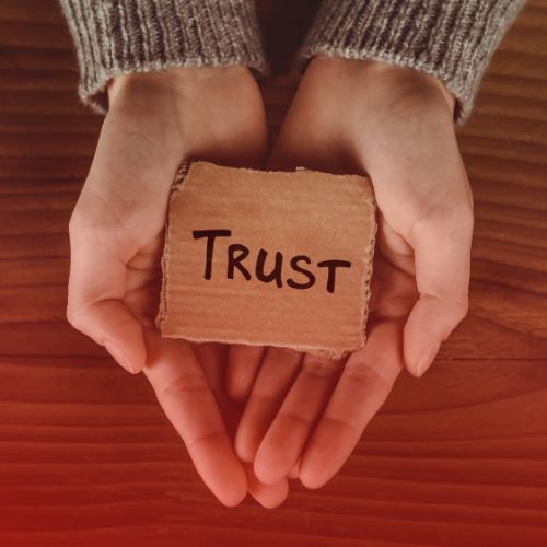 hands holding a card with the wording "trust" on it